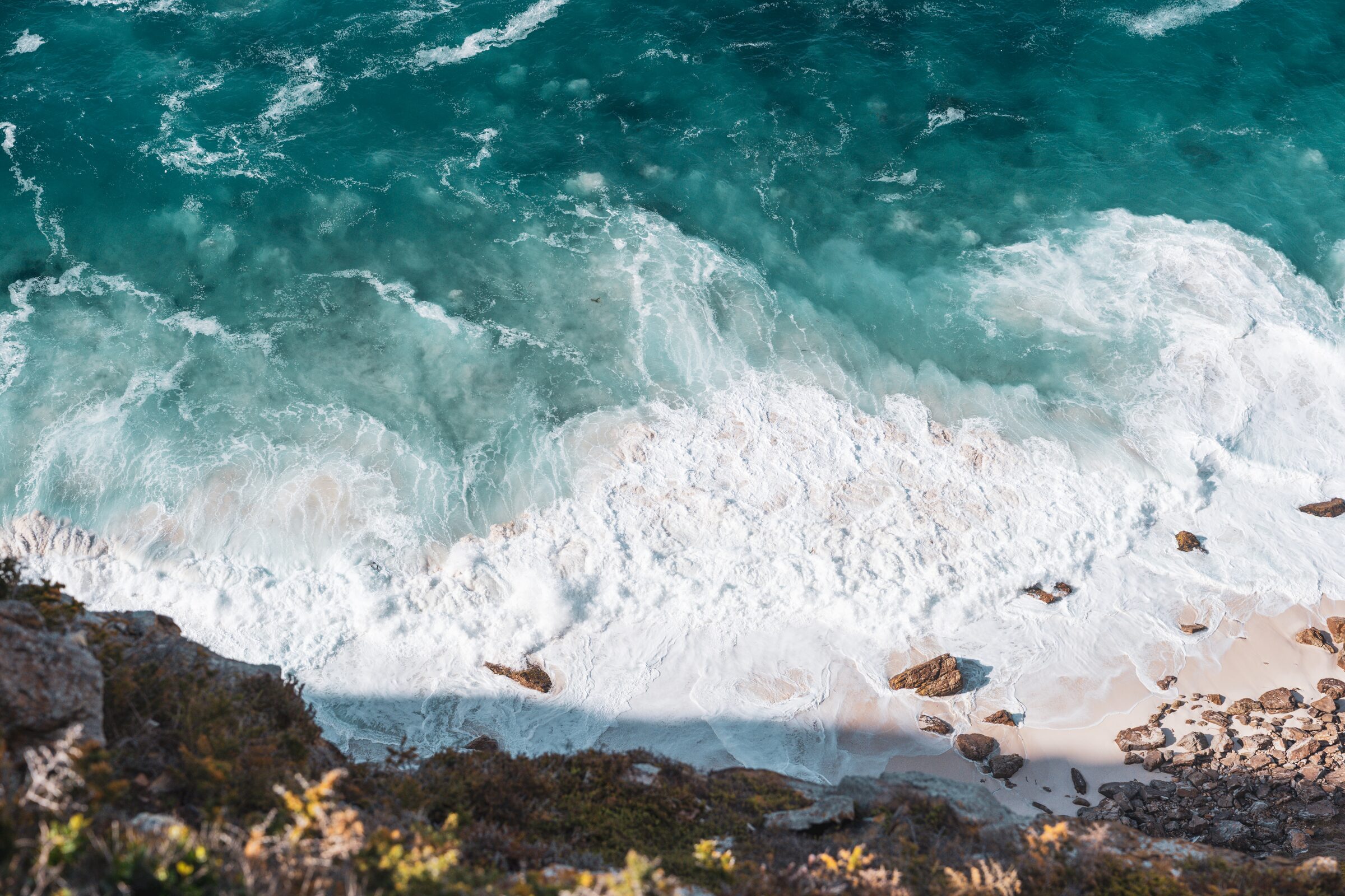Turquoise surf on the rocks below the house